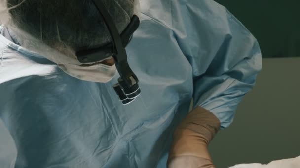Médico vestindo roupas protetoras realizando cirurgia usando equipamentos esterilizados — Vídeo de Stock