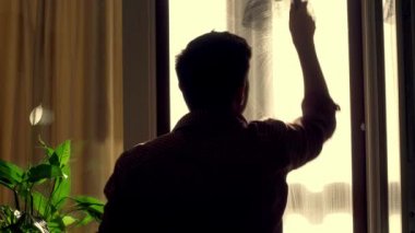 Bir işçi evdeki pencereyi temizler, özel aletler kullanır.