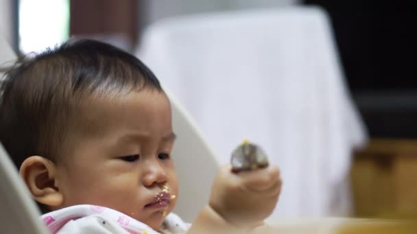 Aziatische baby eten door hemzelf — Stockvideo
