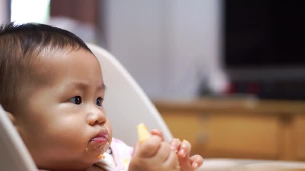 Asiático bebê comer comida por si mesmo — Vídeo de Stock