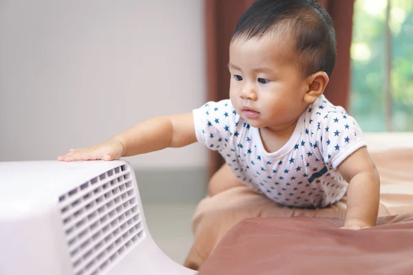 Asian baby curious looking at mobile air conditioner