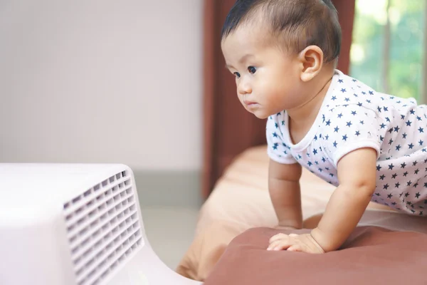 Asian baby curious looking at mobile air conditioner — Stock Photo, Image