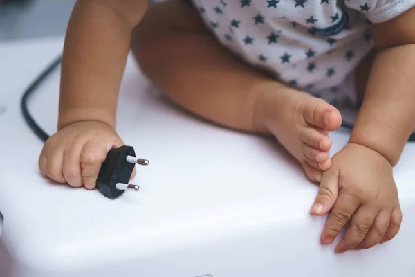 Asian baby curious about electronic plug — Stock Photo, Image