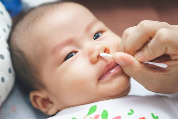 Материнская рука чистит детские уши и нос — стоковое фото