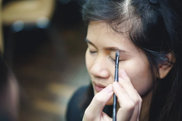 Makeup artist applies eyebrow