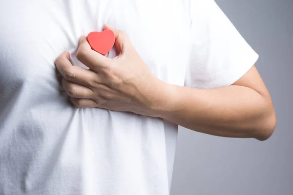 Una mano de hombre con objeto de madera corazón rojo — Foto de Stock