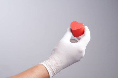 El ahşap kalp şekli nesne tutan lateks eldiven giymiş