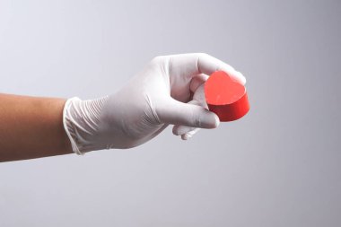 El ahşap kalp şekli nesne tutan lateks eldiven giymiş