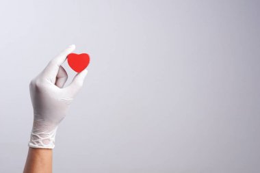 El ahşap kalp şekli nesne tutan lateks eldiven giymiş