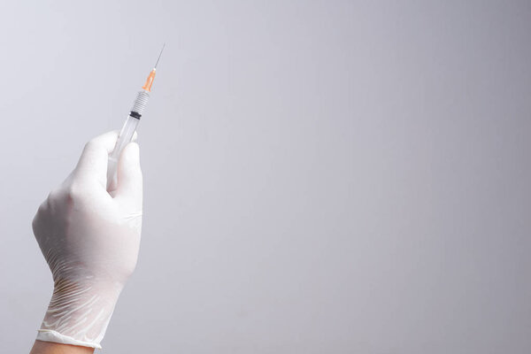 Hand wearing latex glove holding syringe with a medicine