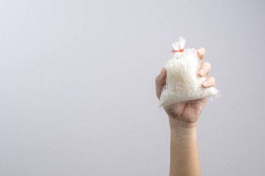 Lastik bant, bir ordin tarafından mühürlü plastik torba pirinç tutan el