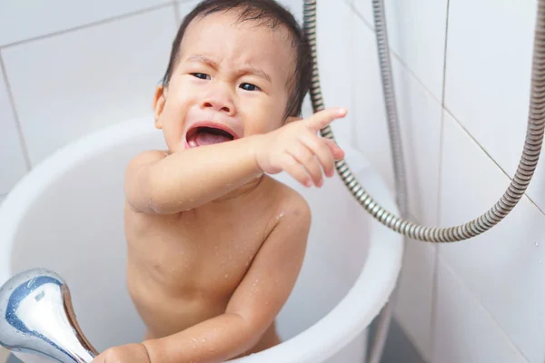 An Asian baby crying while taking a shower
