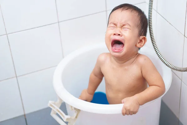 An Asian baby crying while taking a shower