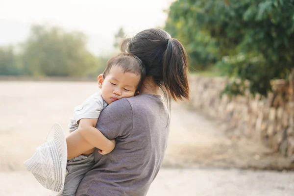 Спящий азиатский ребенок, которого держит его мать — стоковое фото