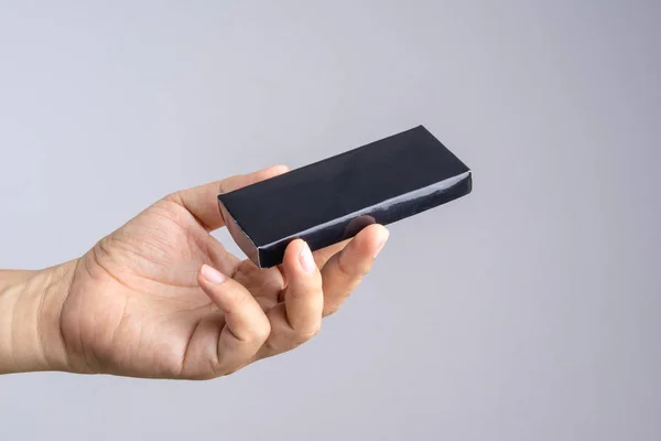 Mão segurando caixa de papel preto — Fotografia de Stock