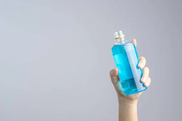 Handen håller öppnade blå alkohol flaska — Stockfoto