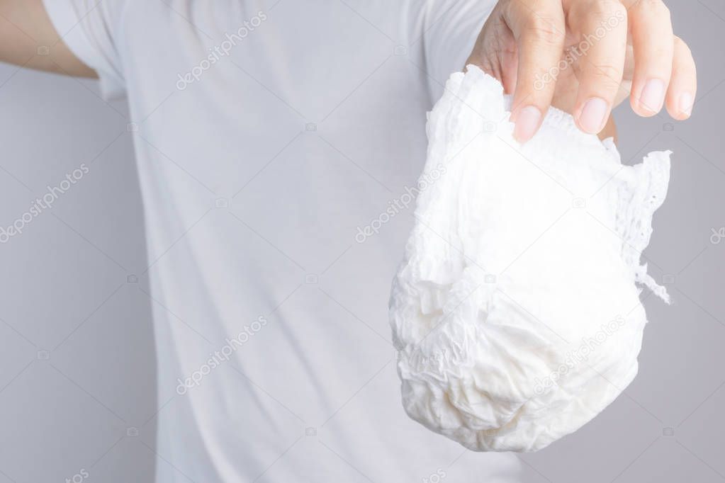 Hand holding used baby diaper