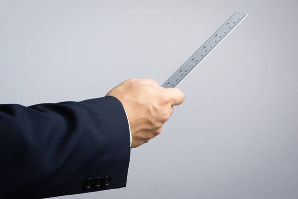 Деловой человек держит линейку в качестве концепции инспектора
