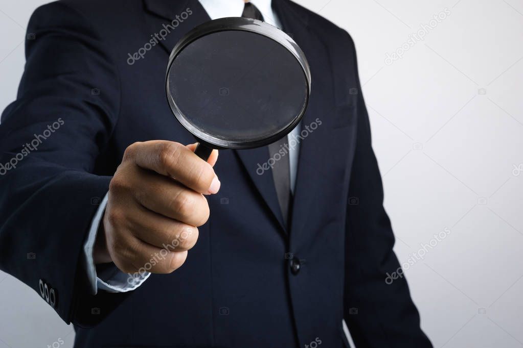 Business man hand holding magnifier for inspection