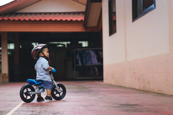 Asiático chico está jugando con bebé equilibrio bicicleta —  Fotos de Stock