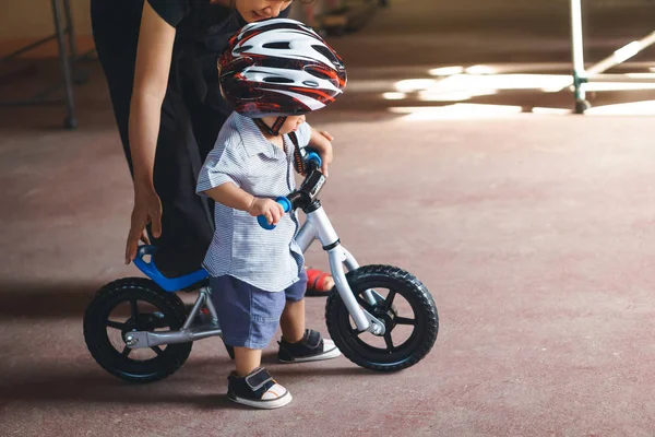 Asiática madre enseñar su hijo a jugar bebé equilibrio bicicleta —  Fotos de Stock