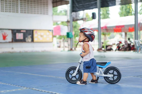Asiático chico está jugando con bebé equilibrio bicicleta —  Fotos de Stock