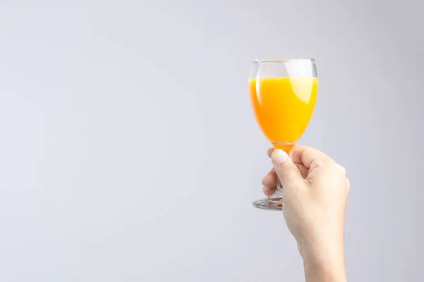 Mão segurando vidro de suco de laranja — Fotografia de Stock