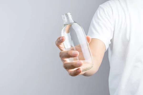 Mão segurando garrafa de água de vidro — Fotografia de Stock