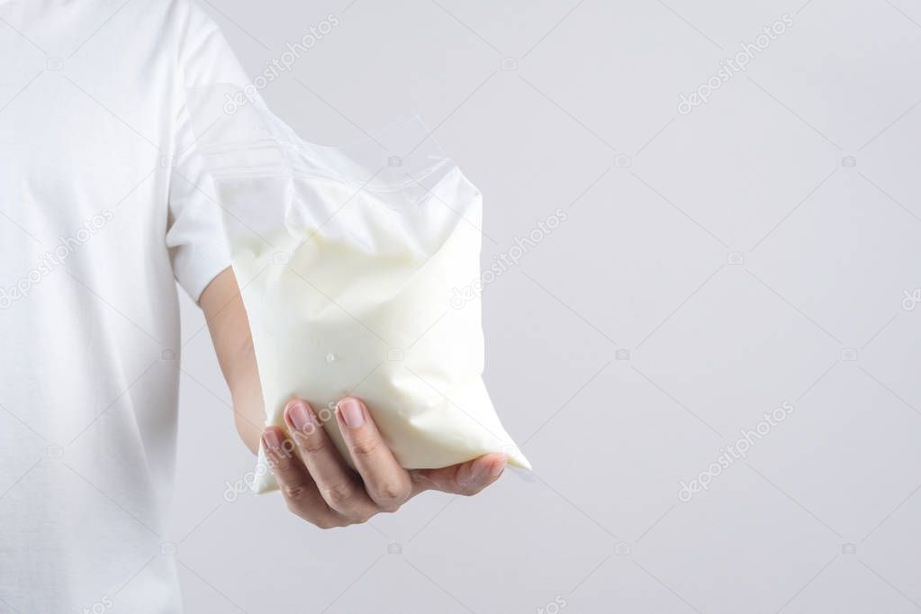 Hand holding a bag of natural yogurt