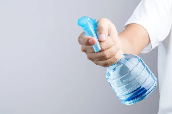 Mão segurando frasco de pulverização de plástico azul contêm água pura — Fotografia de Stock