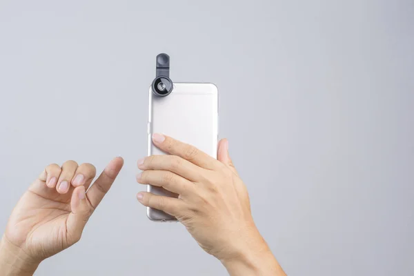Mão segurando telefone inteligente equipado com lente de extensão — Fotografia de Stock