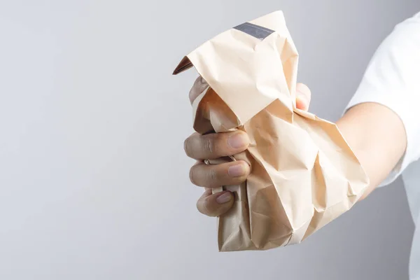 Mano sosteniendo crumble bolsa de papel marrón —  Fotos de Stock