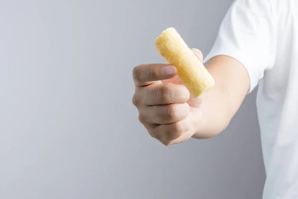 Mão segurando lanche crocante amarelo feito de milho doce — Fotografia de Stock