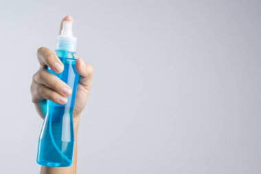 Ayna cam temizleyici veya alkol beyaz zemin üzerine mavi sıvı normalde temizlik plastik sprey şişe tutan el içeren