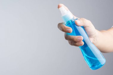 Ayna cam temizleyici veya alkol beyaz zemin üzerine mavi sıvı normalde temizlik plastik sprey şişe tutan el içeren