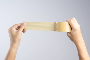 Kahverengi ambalaj bandı rulo beyaz arka planda tutan el