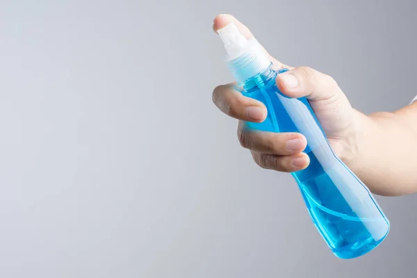 Hand holding plastic spray bottle with blue cleaning liquid normally contain mirror glass cleaner or alcohol on white background