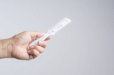 Saç Dilimleme için bıçak bıçak kesme aracı tarak ya da saç beyaz arka planda ayarlamak tutan el