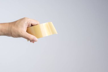 Kahverengi ambalaj bandı rulo beyaz arka planda tutan el