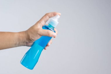 Ayna cam temizleyici veya alkol beyaz zemin üzerine mavi sıvı normalde temizlik plastik sprey şişe tutan el içeren