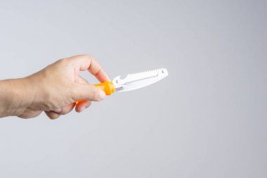 Turuncu kulplu plastik Meyve soyucu beyaz arka plan üzerinde tutan el