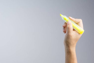Beyaz arka plan üzerinde bir renk kelime marker yazmak için sarı fosforlu kalem tutan el