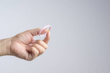 Beyaz arka plan üzerinde pembe elastik saç lastiği tutan el