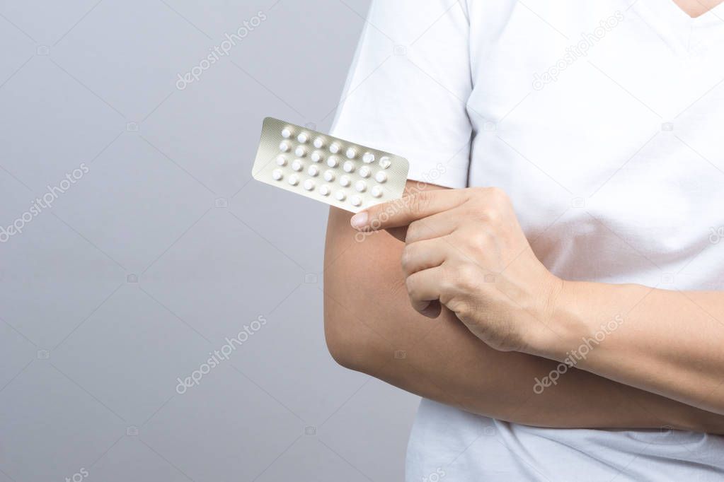 Woman hand holding pack of contraceptive pills, birth control medicine on grey background