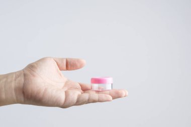 Krem veya makyaj toz küçük plastik kap beyaz arka plan üzerinde tutan el