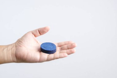 Otomatik çamaşır suyu tuvalet kase temiz leke sökücü mavi sekmesini veya tablet floş tank beyaz arka planda tutan el