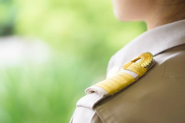 Thai teachers in official uniform focus on golden stripe shoulder accessory