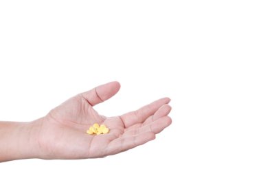 Beyaz zemin üzerine sarı tıbbi hap tutan el