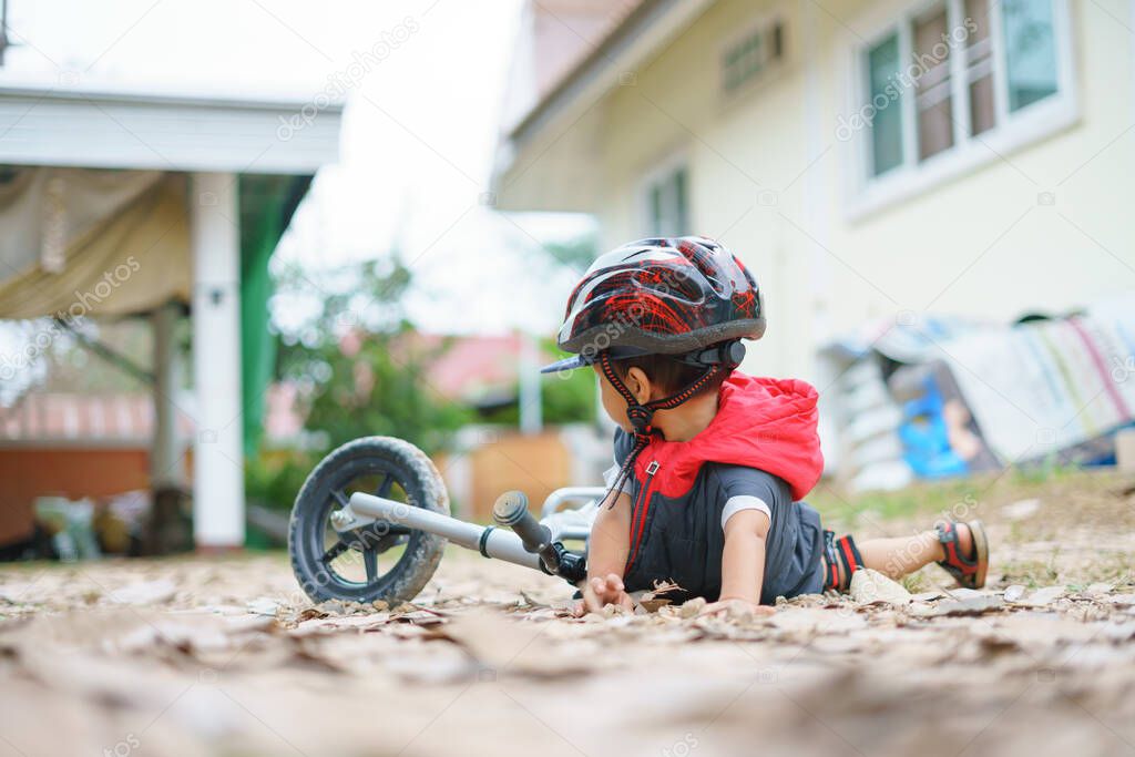 Asian boy about 2 years is riding baby balance bike and fall