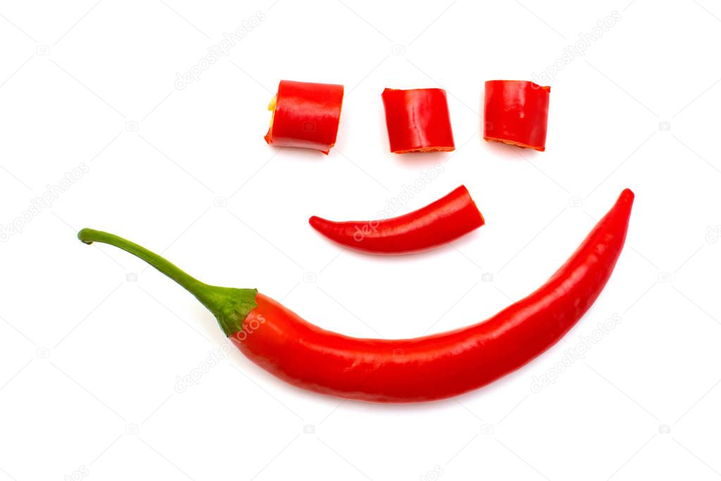 Red chili pepper cut into slices lined with a human face like a clown isolated on white background. Creative spicy sharp. Flat lay, top view